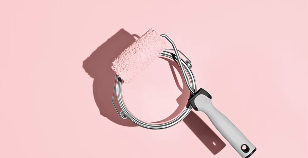 Farbrolle mit rosaner Farbe auf rosanem Hintergrund